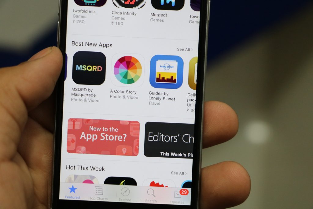 Close up of a hand holding a phone displaying the Apple app store.