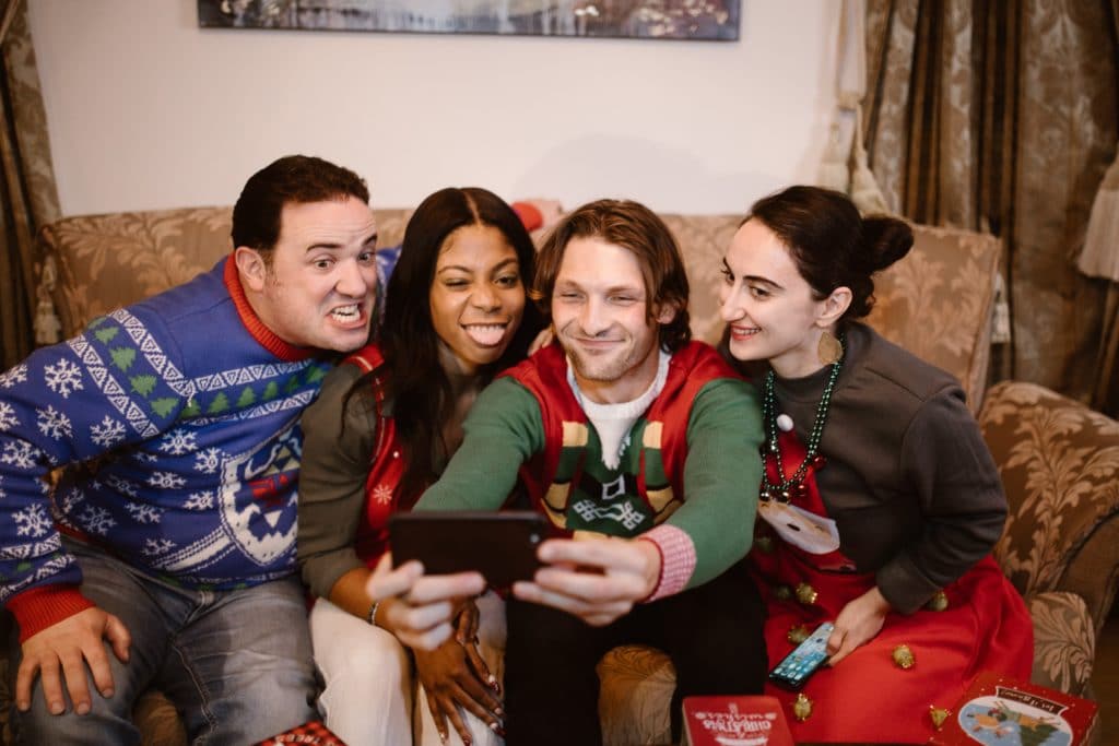 A group of people taking a selfie in ugly Christmas sweaters.
