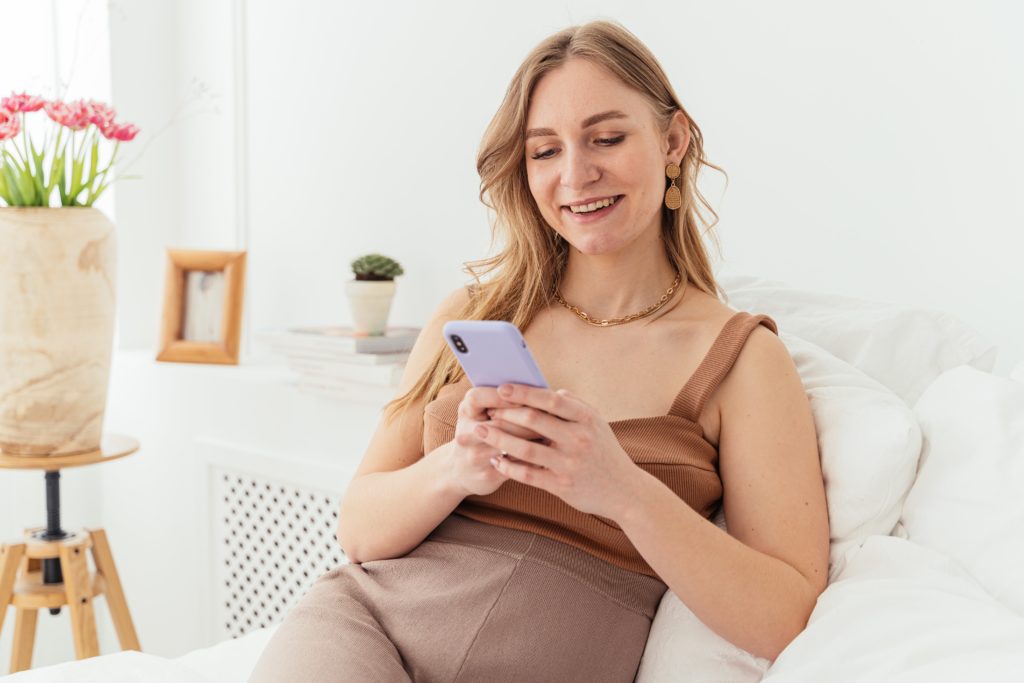 Blond woman smiling while looking at phone.