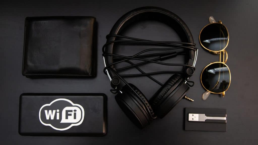 Headphones, sunglasses, USB cord, wallet, and WiFi symbol against a black background.