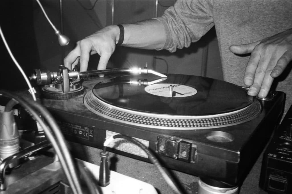 Black and white photo of a DJ's hands on a turntable
