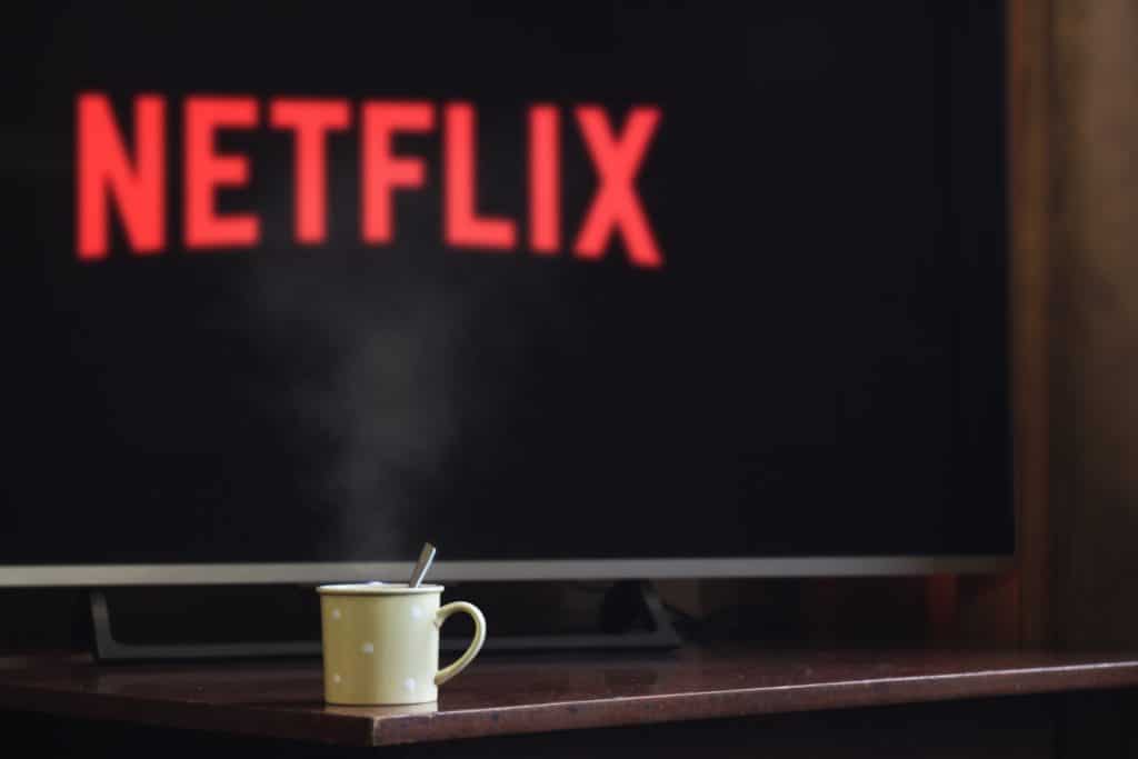 A mug of hot chocolate in front of a TV displaying the Netflix logo