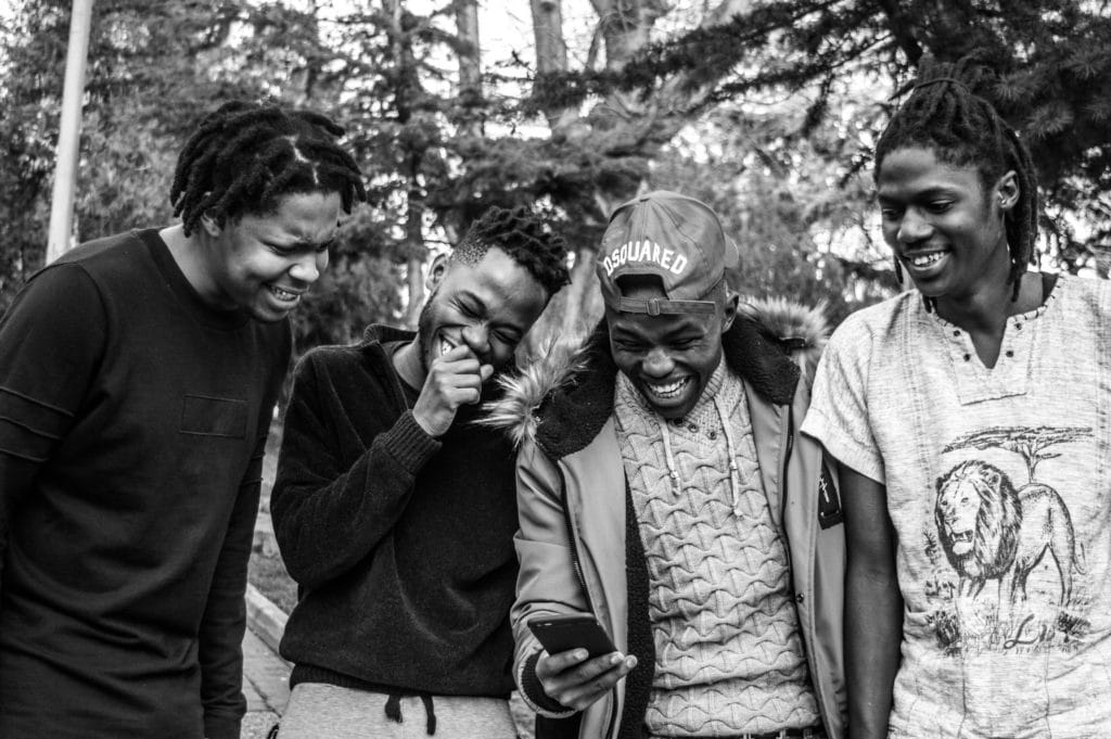 A group of friends looking at a smartphone and laughing.