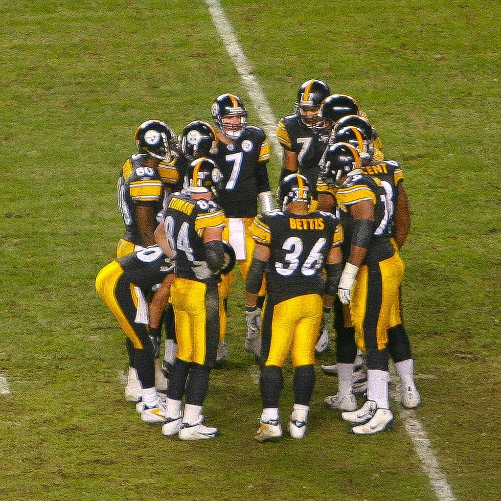 Pittsburgh Steelers in a huddle. Offensive players gather in a rough circle out of hearing of the opposing defense to plan the next play.