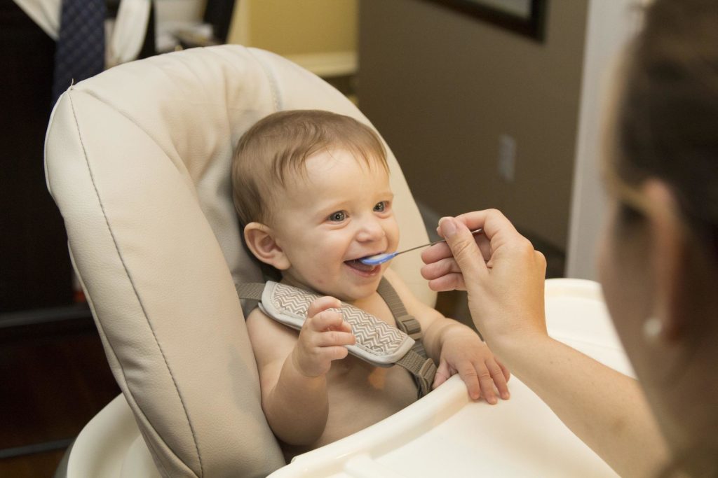 A baby being fed with a blue spoon