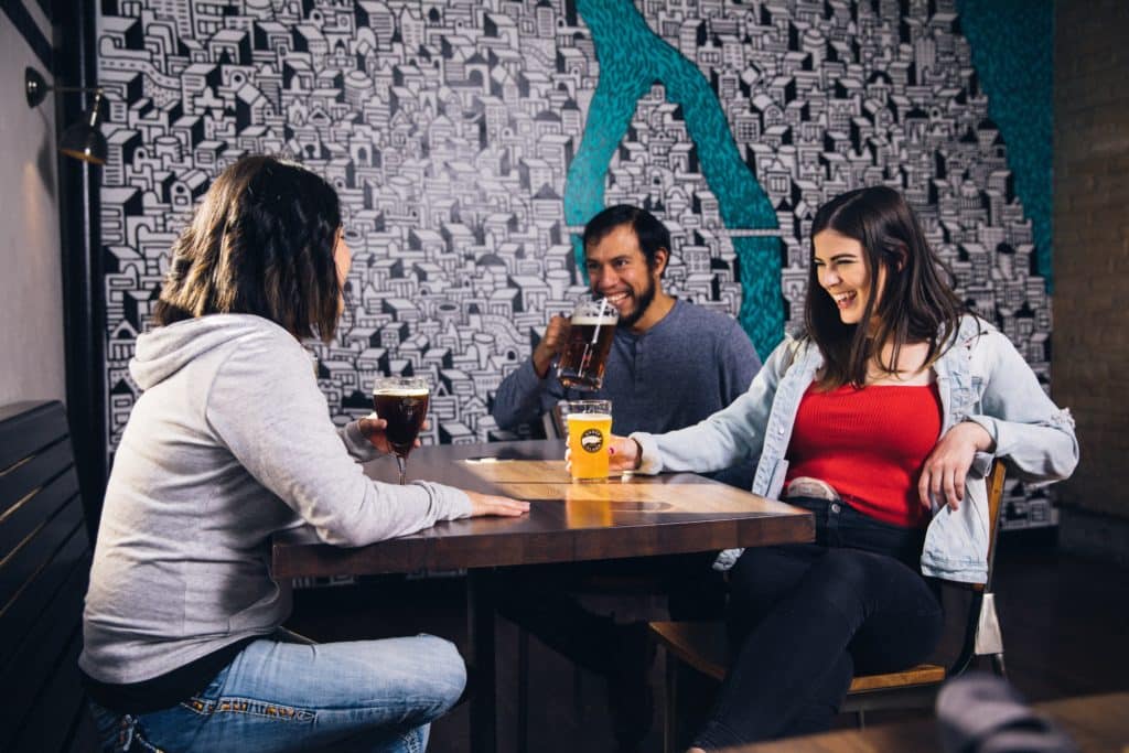 A group of friends sitting at a table having beers at a bar