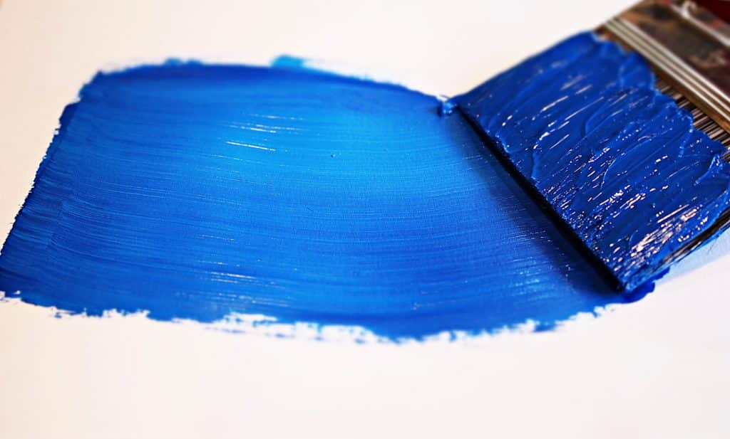A paintbrush painting a stroke of blue