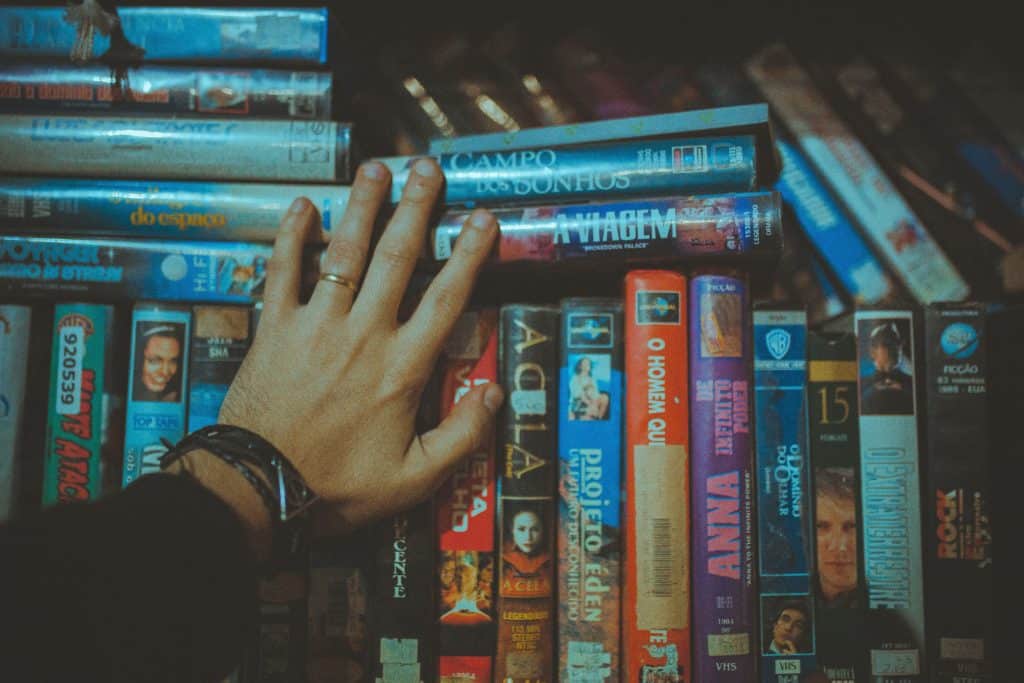 A hand touching a shelf stacked with VHS tapes