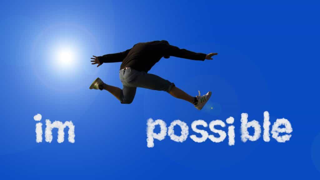 A person jumping in the sky with text under him written in what looks like clouds that says "im possible"