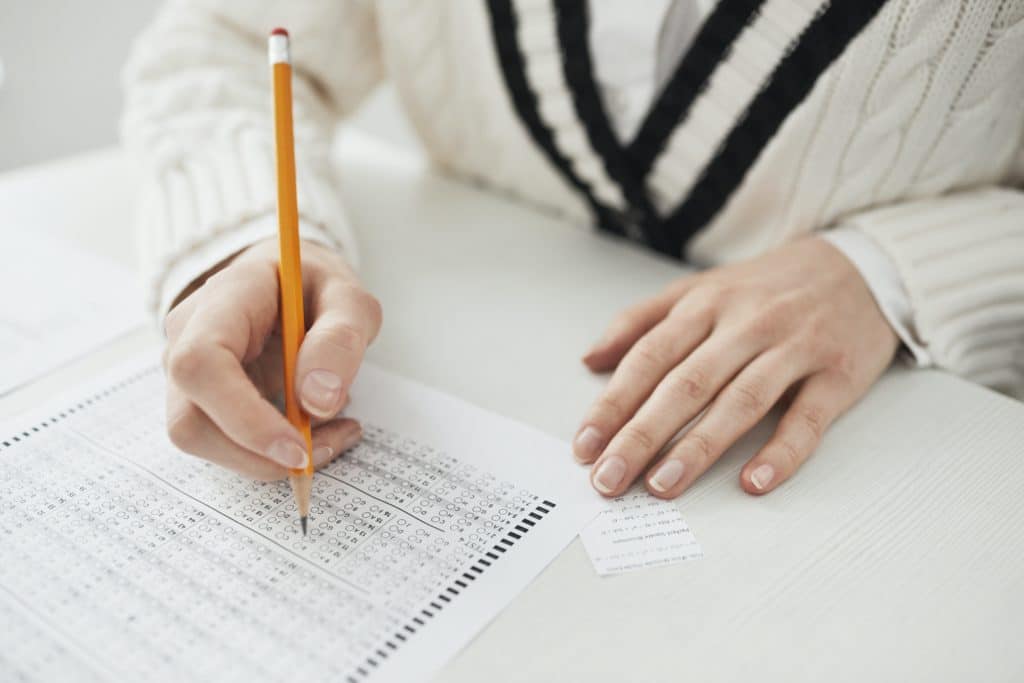 A person in a white sweater with black stripes taking a multiple choice exam