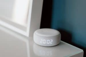 Close-up of a white Amazon Echo Dot displaying the time.