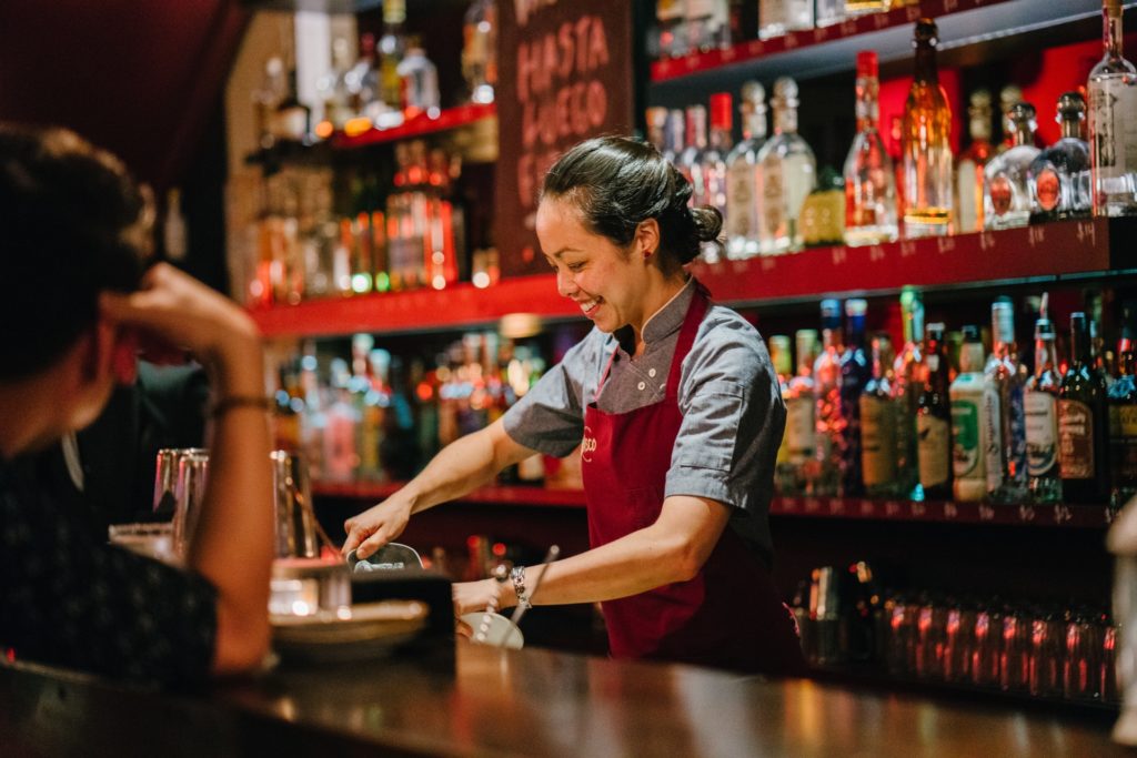 Friendly female bartender mixing a drink
