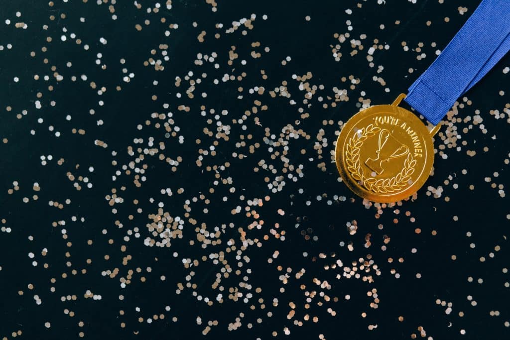 Gold medal on a blue ribbon against a black background with confetti