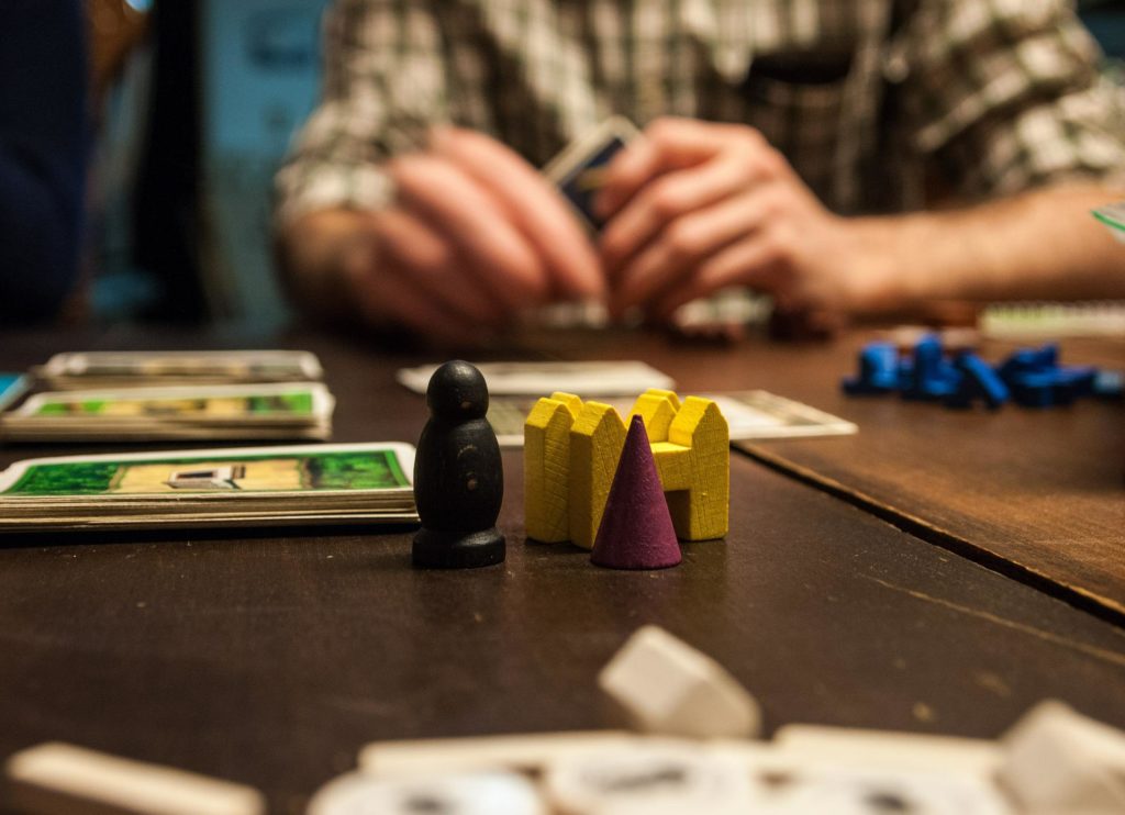Close up of a strategy game with a person playing it, holding cards