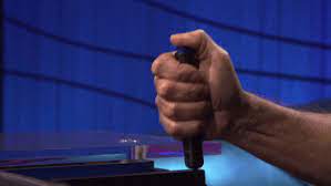 Close up of a hand holding a Jeopardy! buzzer