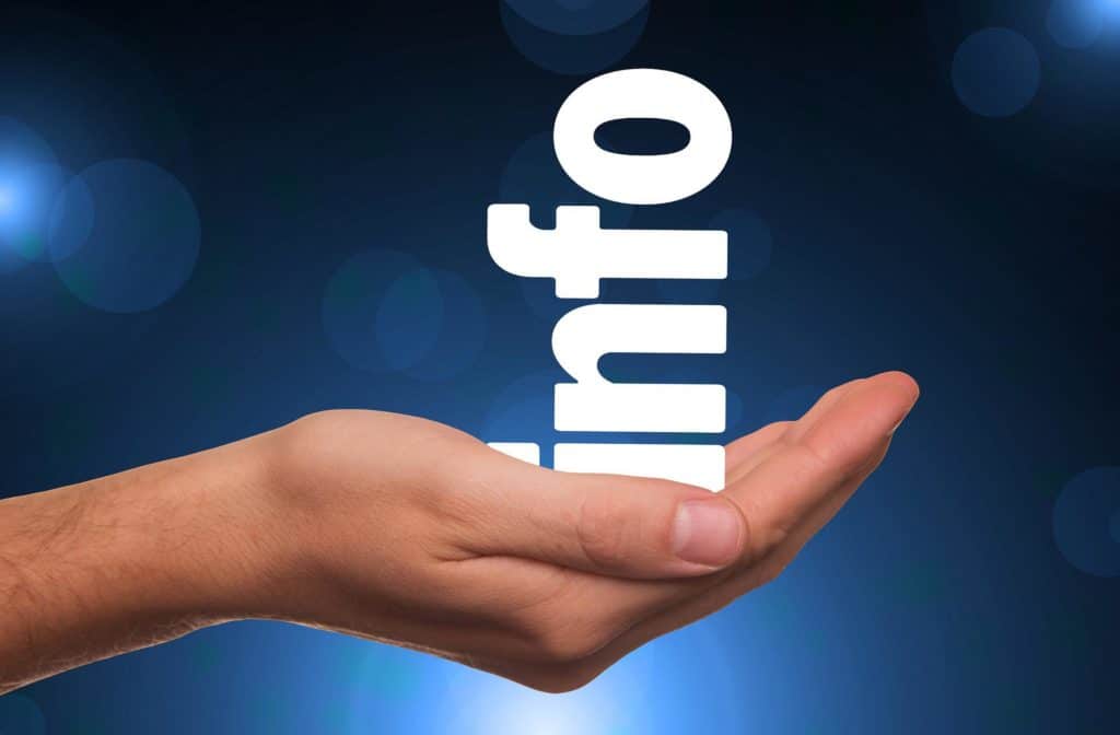 A hand holding the word "info" written out in white letters against a blue backdrop