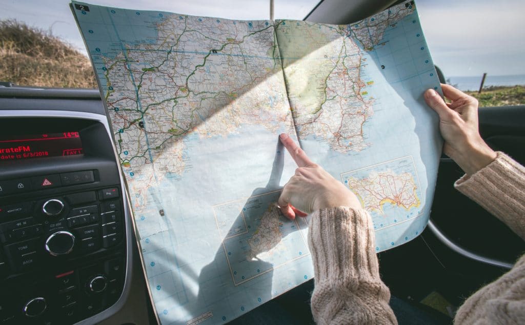 A woman in a car pointing to a map she's holding up