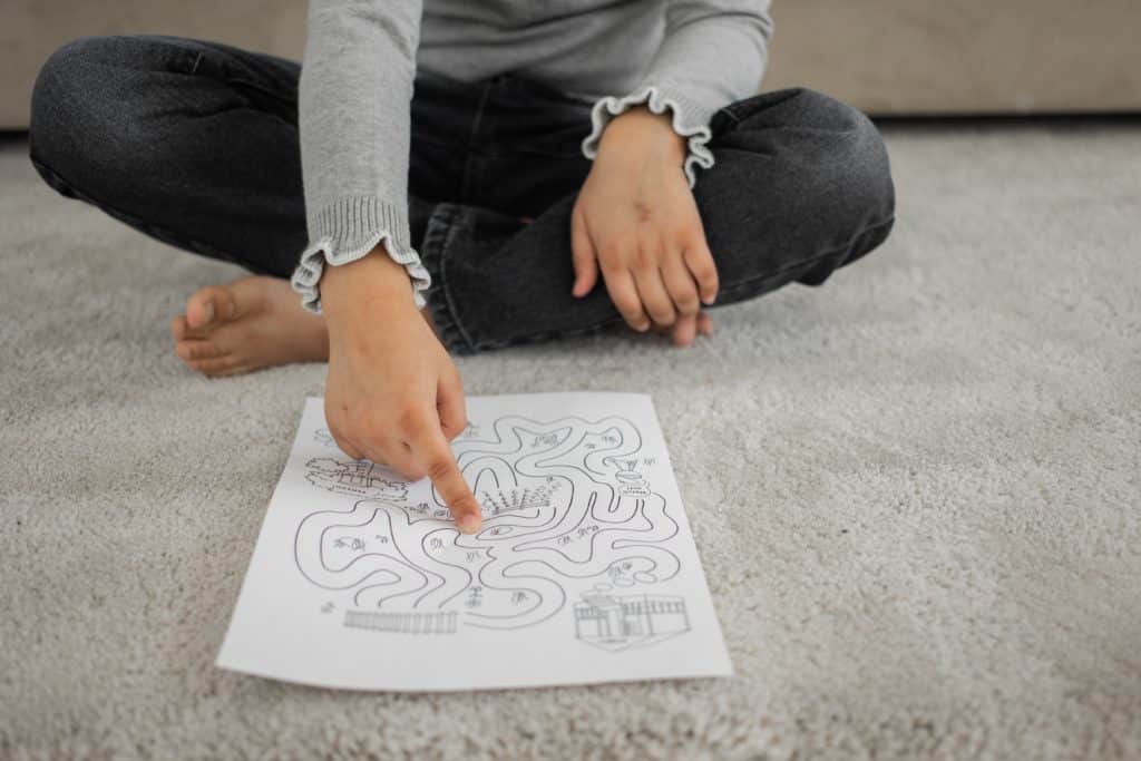 A kid pointing to a paper with a puzzle on it