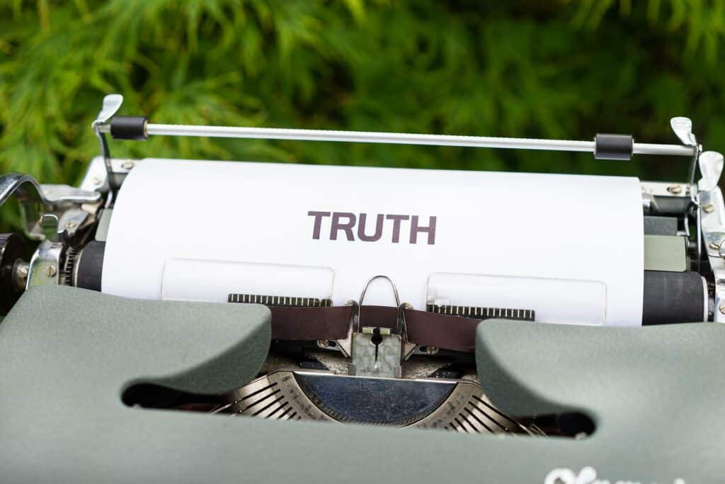 A typewriter typing out the word "TRUTH" on a white piece of paper