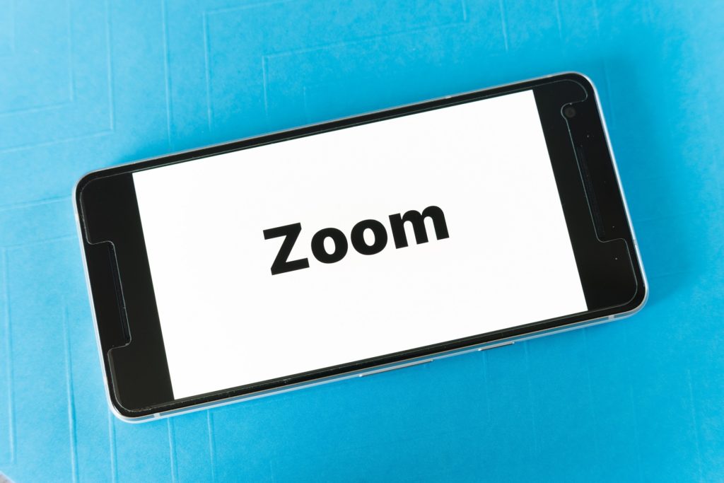 Smartphone displaying a white screen with the word "Zoom" typed out in black letters