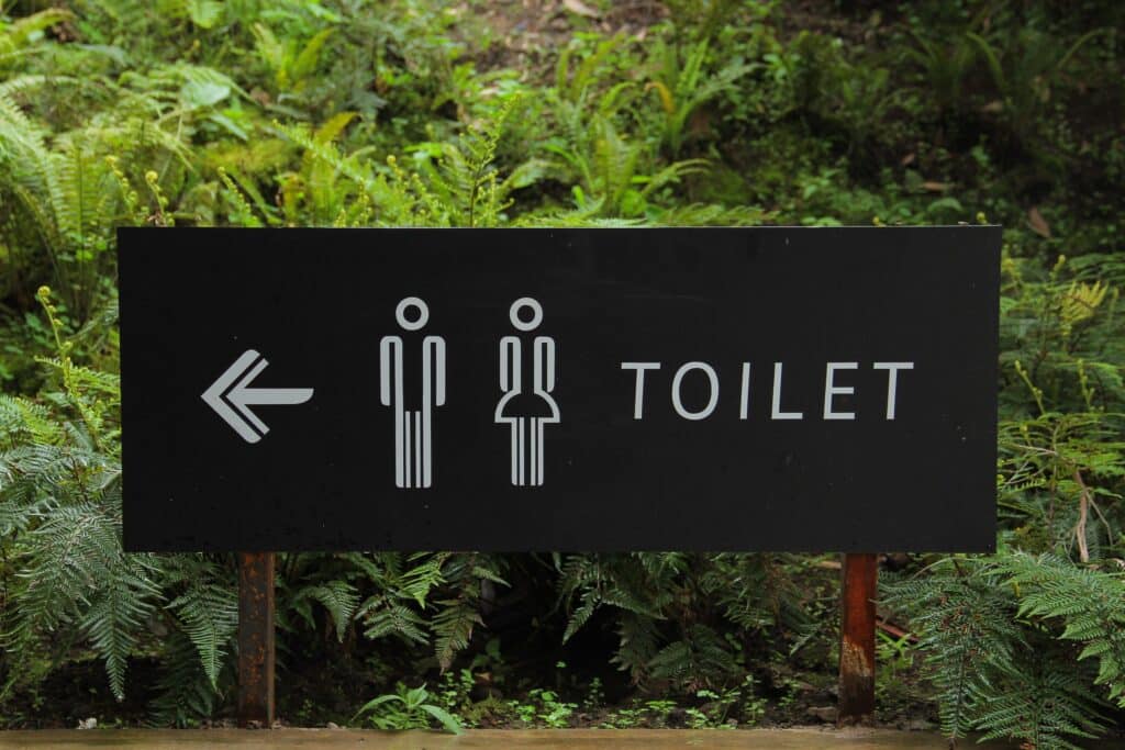 Photo of a black toilet sign in the outdoors.