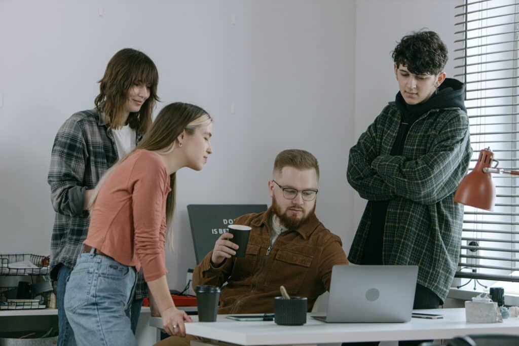 A group of men and women standing around a laptop