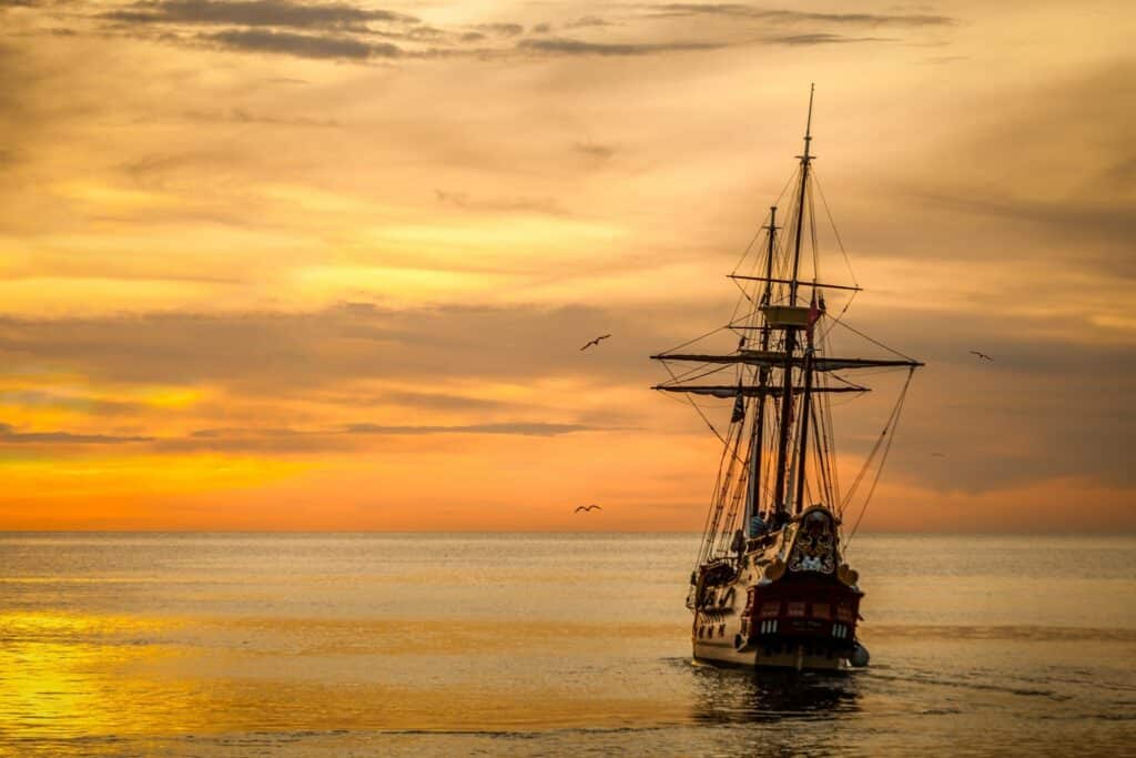 A ship sailing on water at sunset