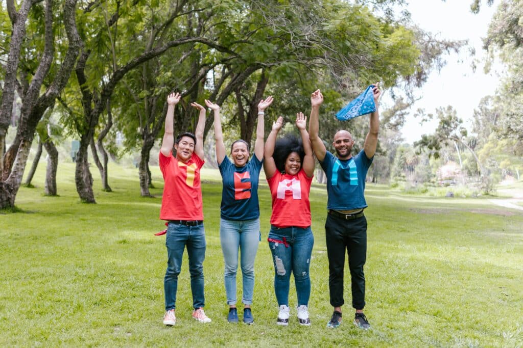 Two women and two men happily standing in a field with red and blue shirts that spell out the word "TEAM"