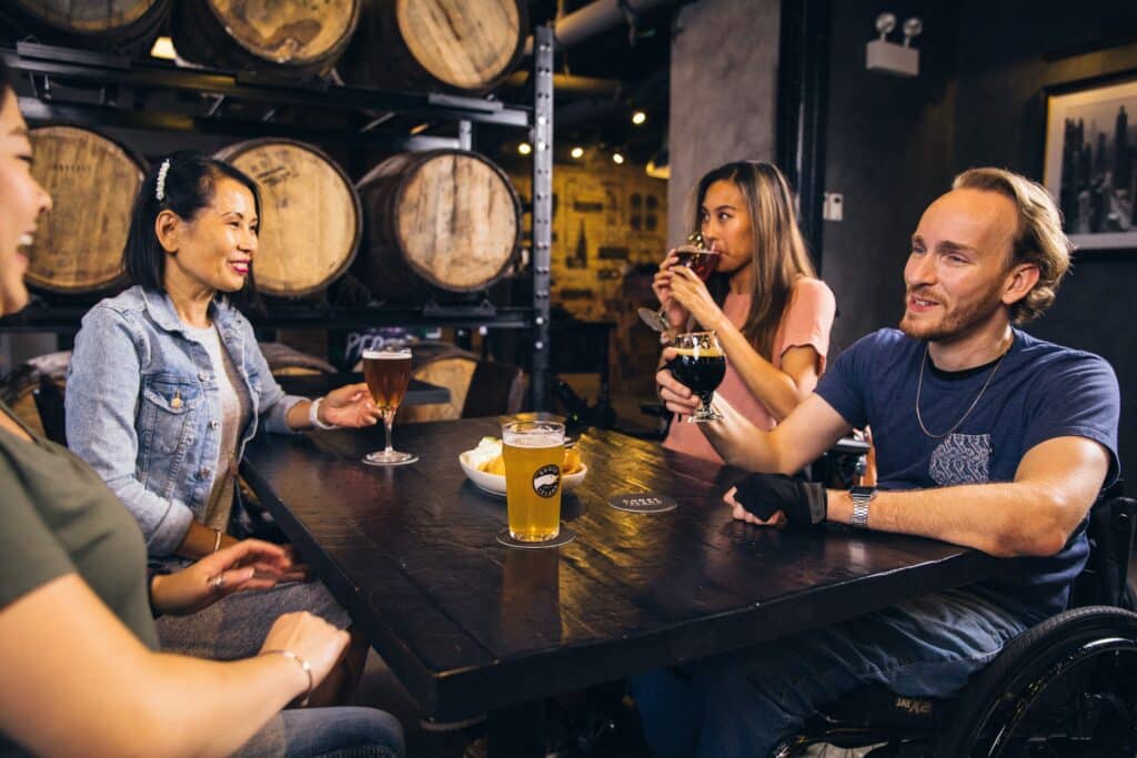Four friends sitting at a table at a brewery having drinks.