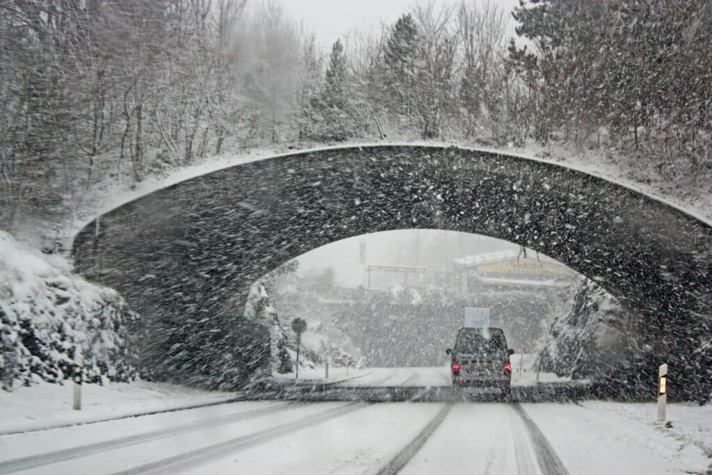 A truck driving under a tunnel in a snowstorm