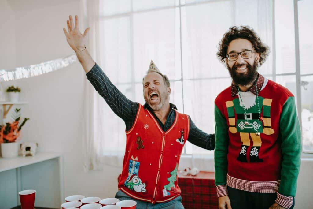 Two men celebrating and wearing ugly Christmas sweaters