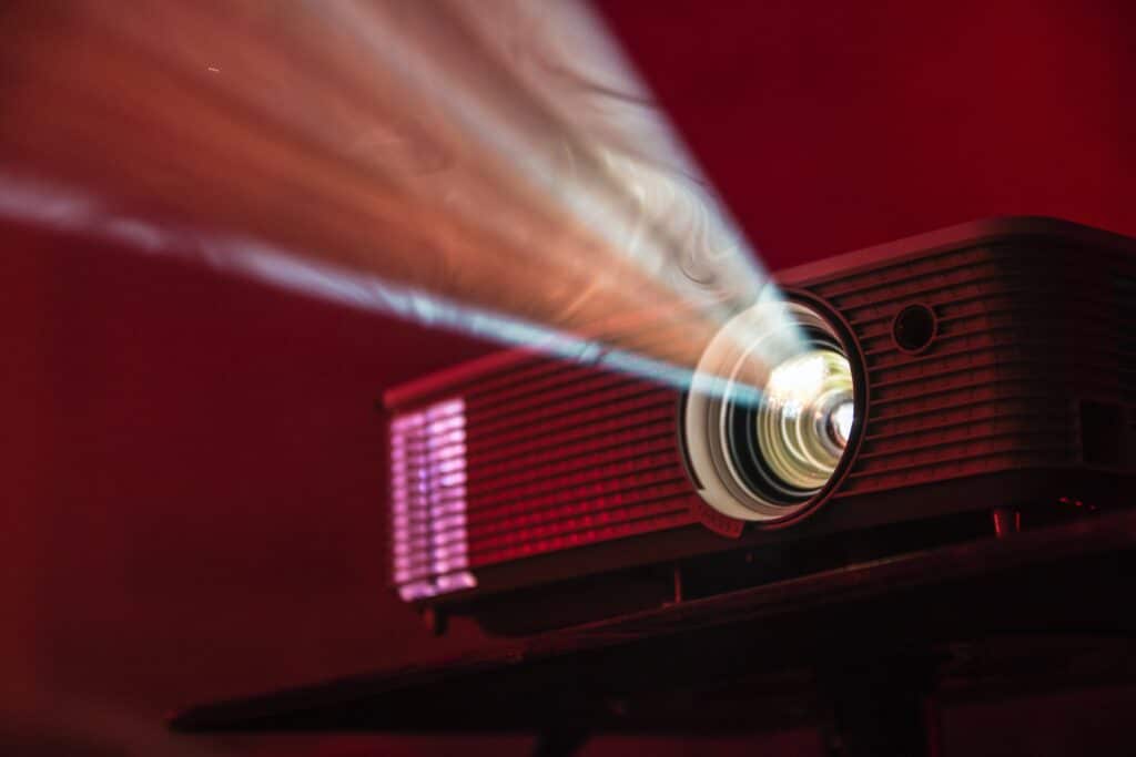 Photo of a projector emanating rays, against a red background