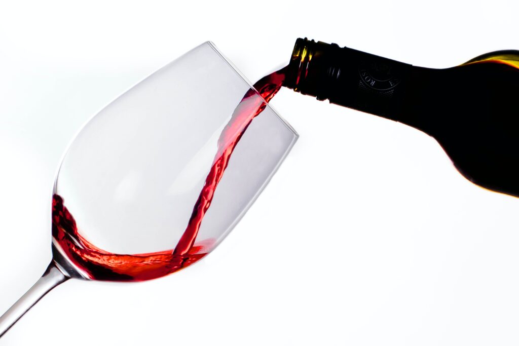 Red wine being poured into a clear wine glass