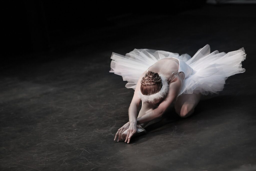 A ballerina crouched over in a pose on the ground