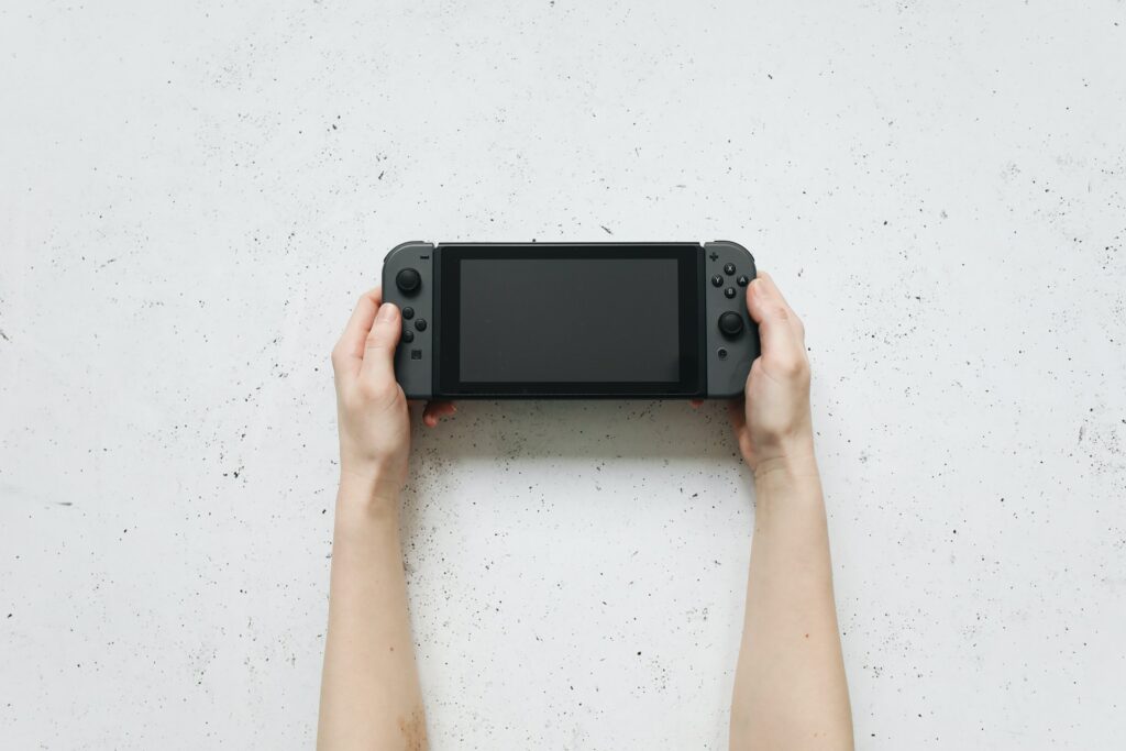 Close up of hands holding a black Nintendo Switch controller