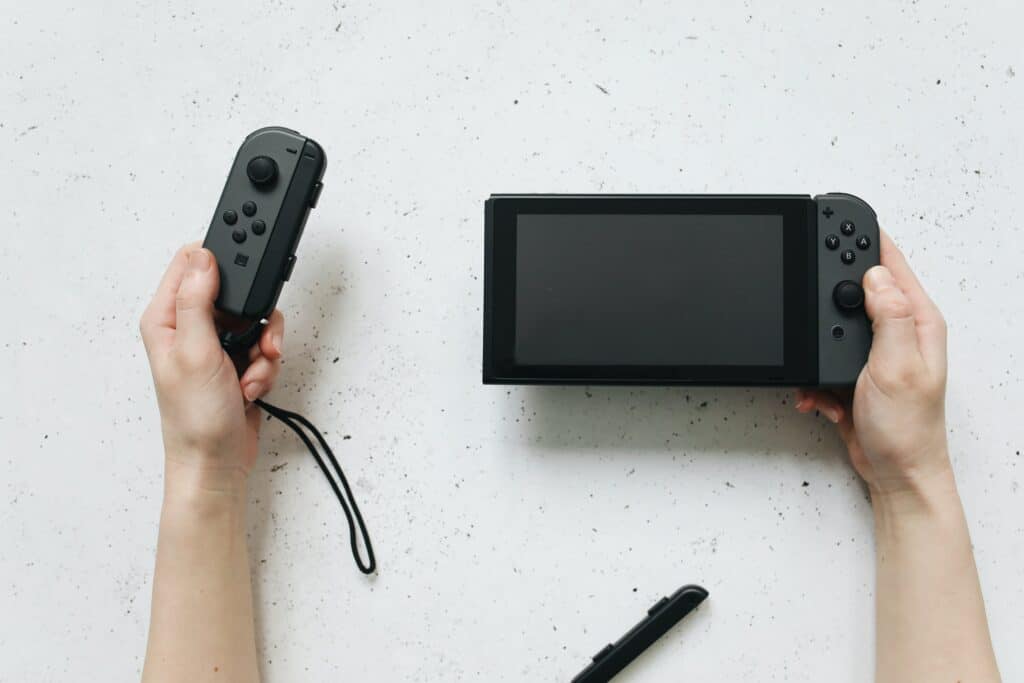 Photo of a hand taking apart a black Nintendo Switch controller.