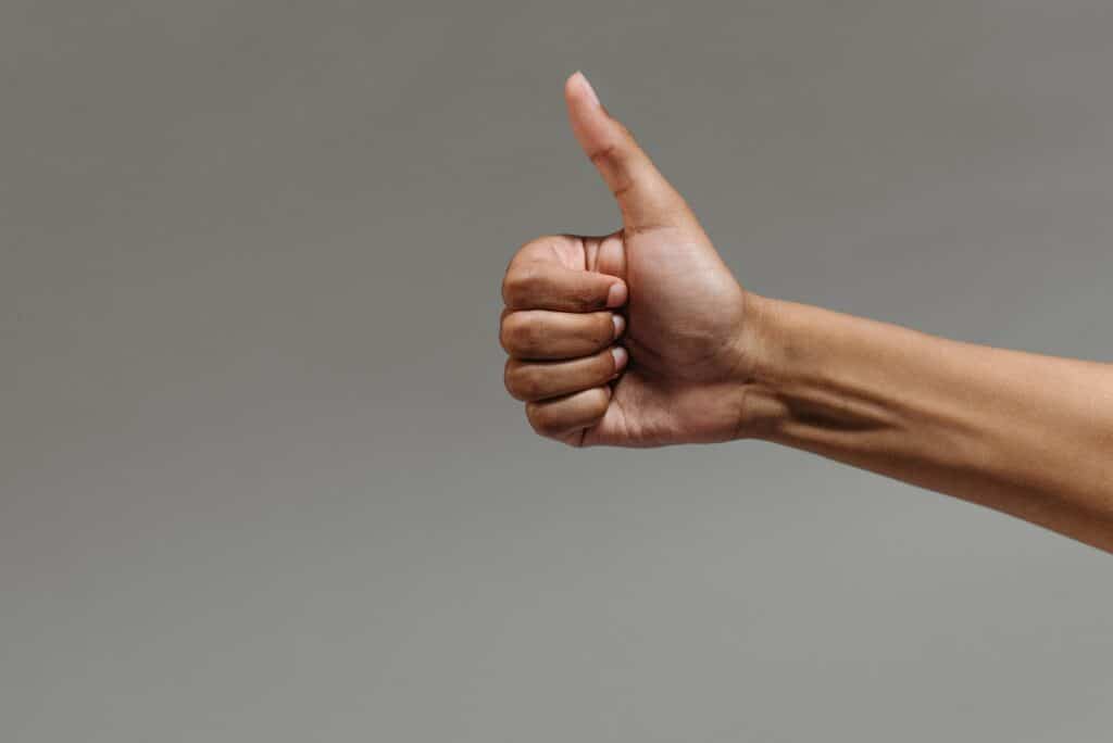 Photo of a hand giving a thumbs up against a grey background
