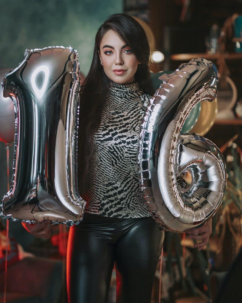 Photo of a young girl holding up balloons that spell out "16"