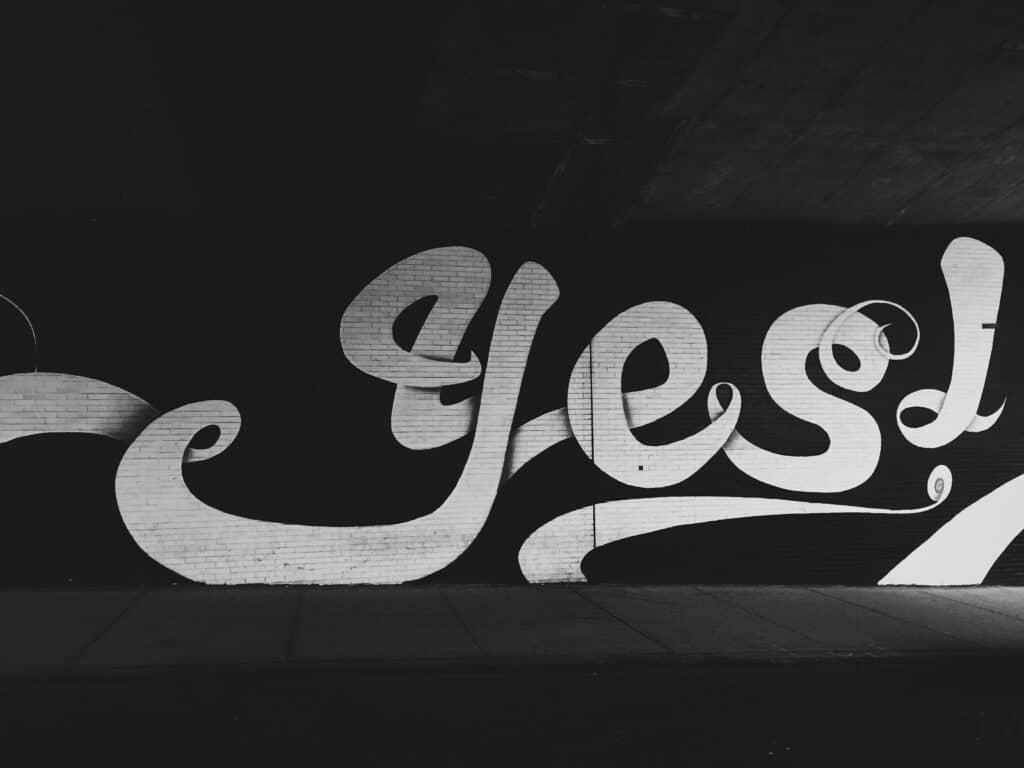 Black and white street art that reads "yes!"