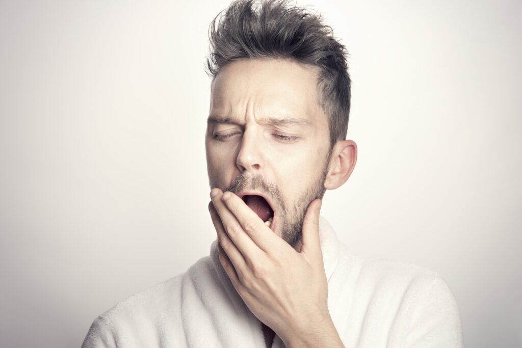 Man in a white collared shirt yawning.