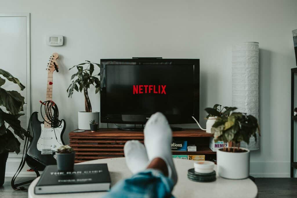 A person's socked feet up on a table in front of a TV streaming Netflix.