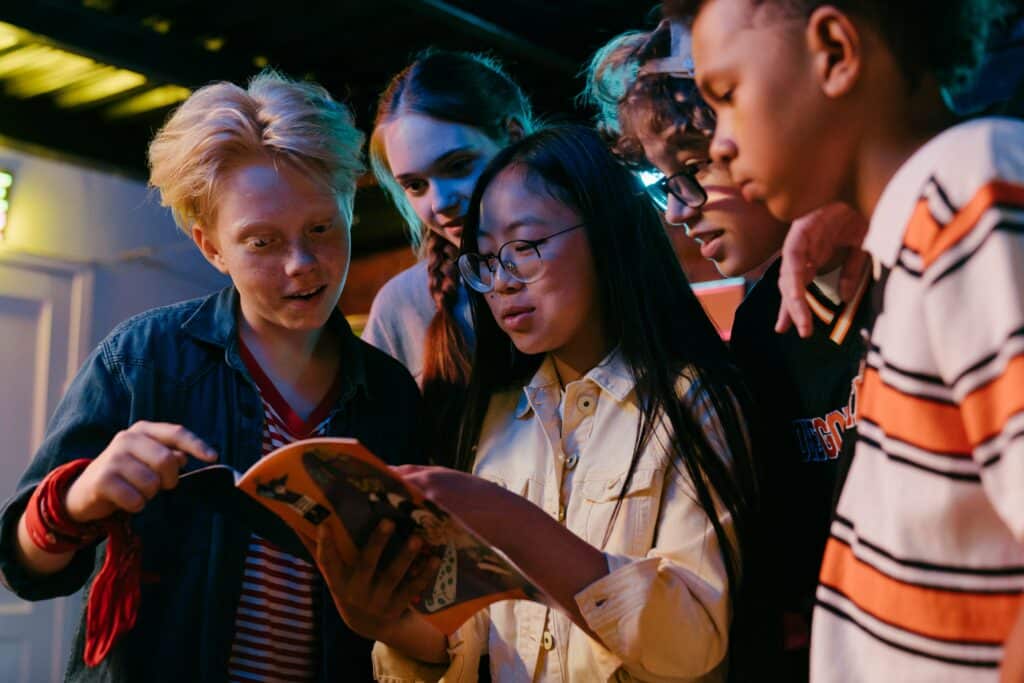 Photo of a group of teenagers all reading a comic book together. 