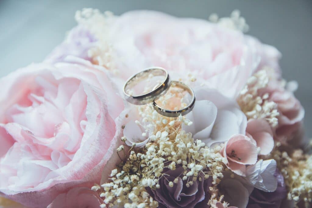 Photo of wedding rings atop a bouquet of flowers