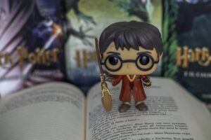 Photo of a Harry Potter Funko Pop on top of an open Harry Potter book, with other Harry Potter books behind him