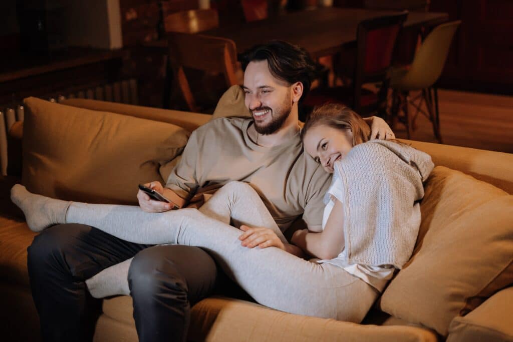 Photo of a couple watching TV on the couch.