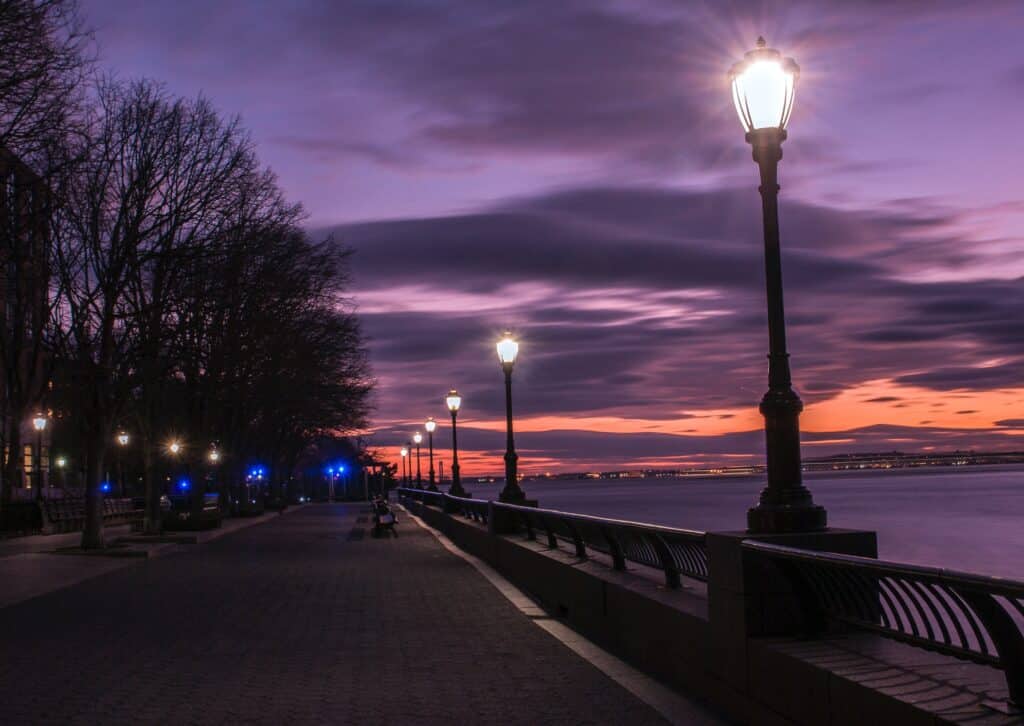 Photo of streetlamps on water against a purple evening sky