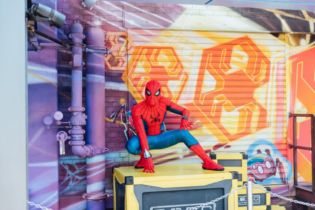 Photo of a person dressed as Spiderman crouching against a colorful graffitied background.