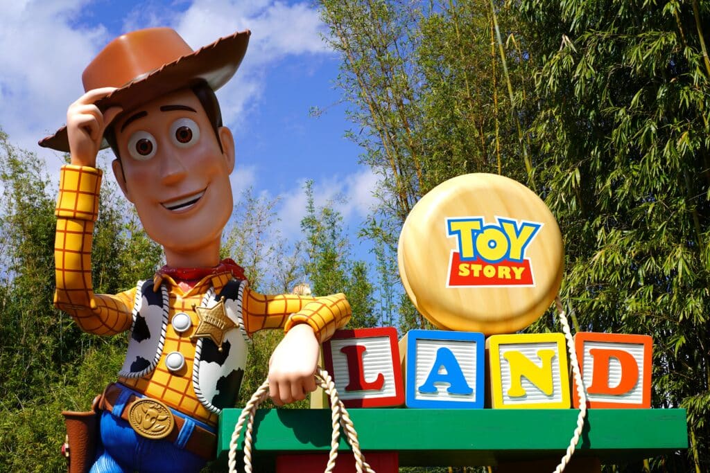 Image of Woody from Toy Story standing next to the Toy Story Land sign