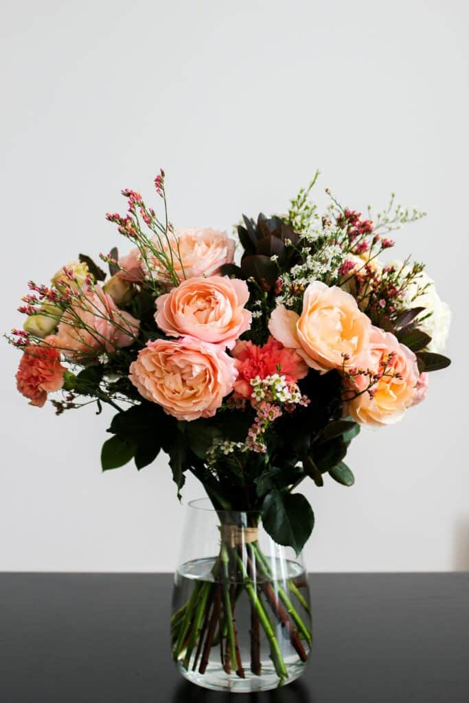 Photo of pink, beige, and red flowers in a clear glass vase