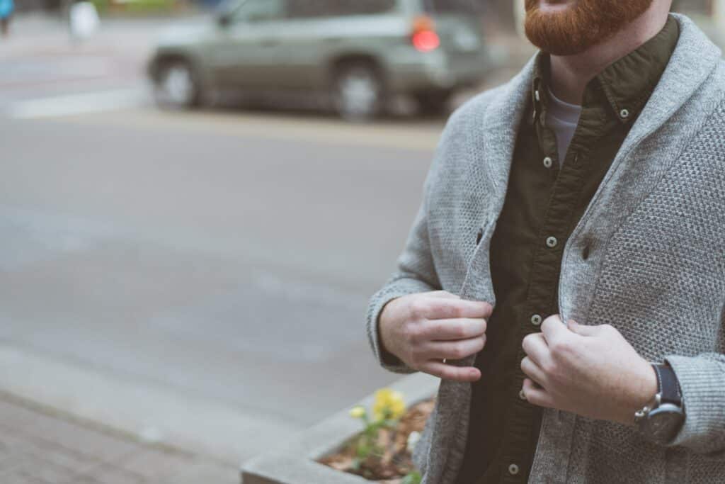 Photo of a man with a red beard wearing a grey button down sweater